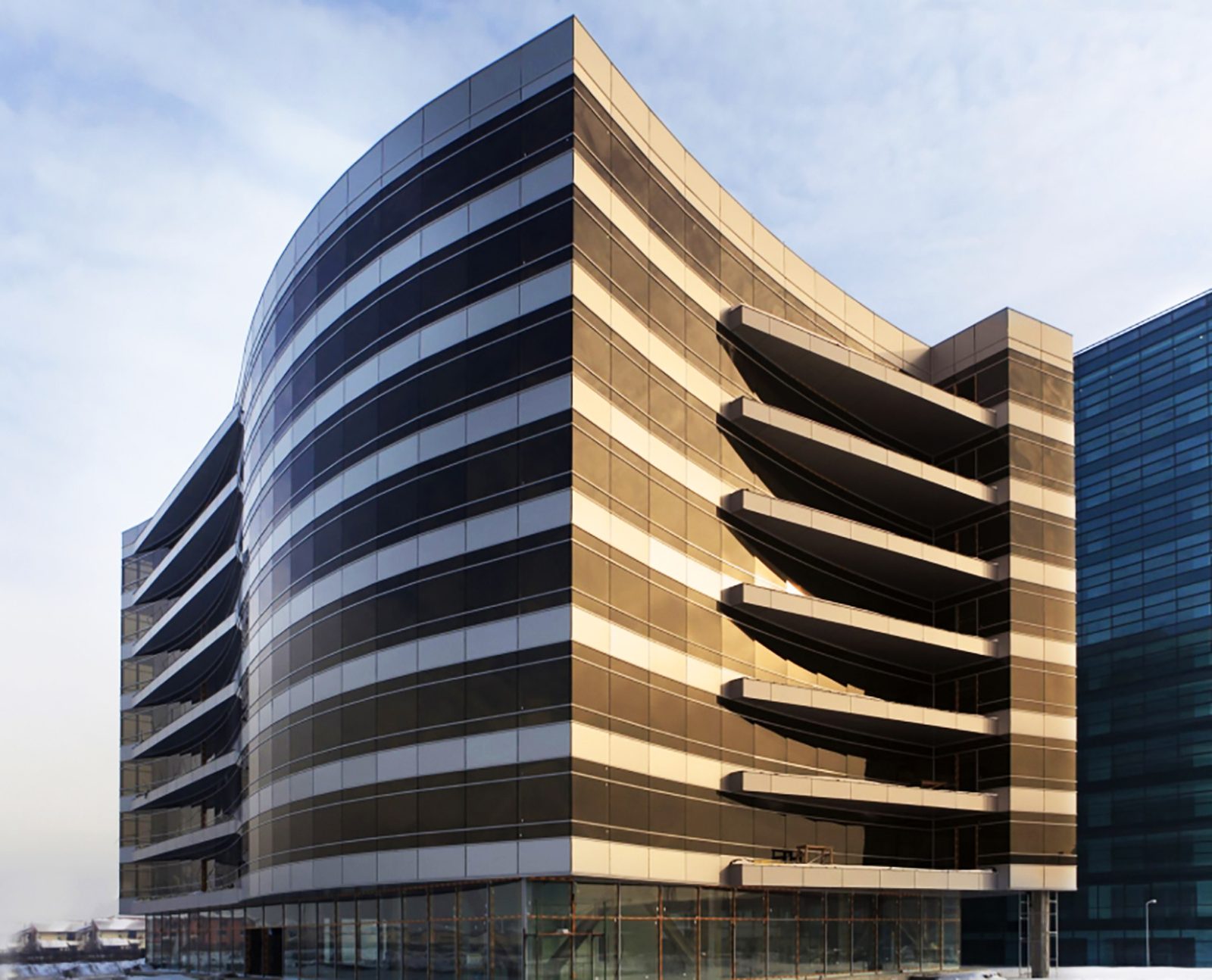 Colțul clădirii construite, cu sticla bronz-auriu prinsă în soarele de iarnă