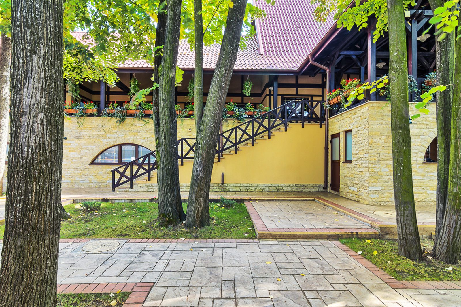 Scara exterioară cu balustradă de lemn, spre terasa cu flori, printre copaci