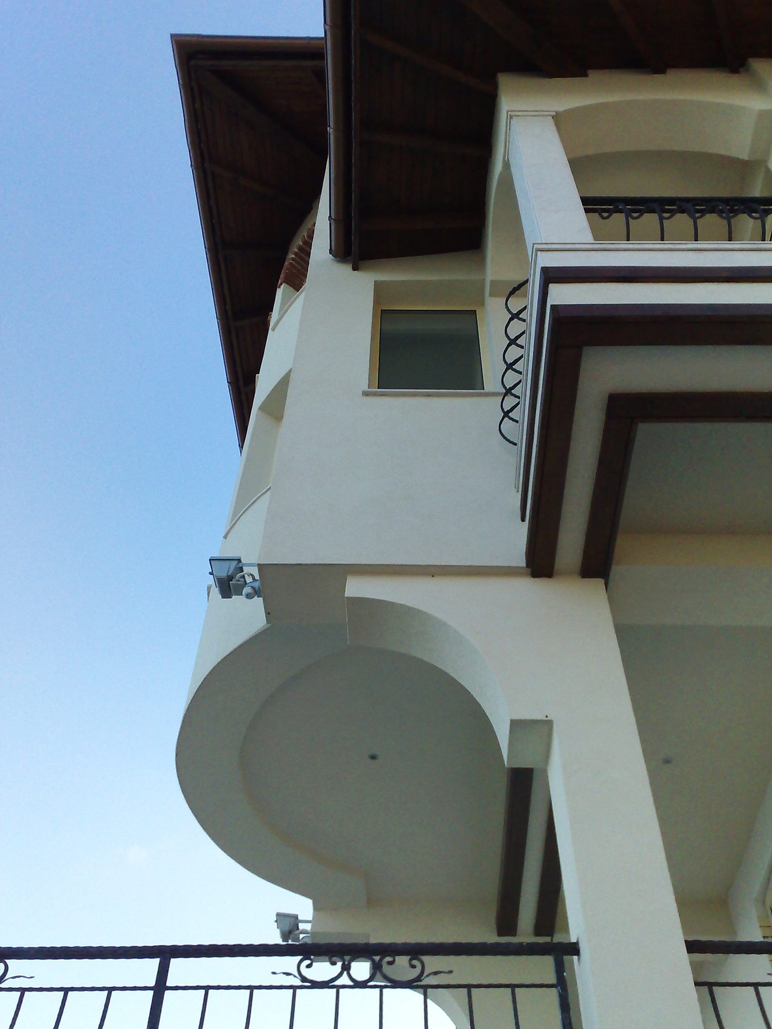 Colțul casei în contraplonjeu: balconul rotunjit în consolă și streașina de lemn