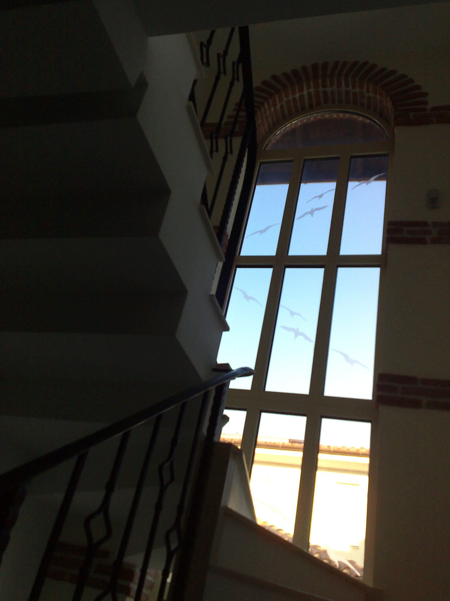 Casa scării, cu balustradă de fier forjat și fereastra înaltă sub arc de cărămidă