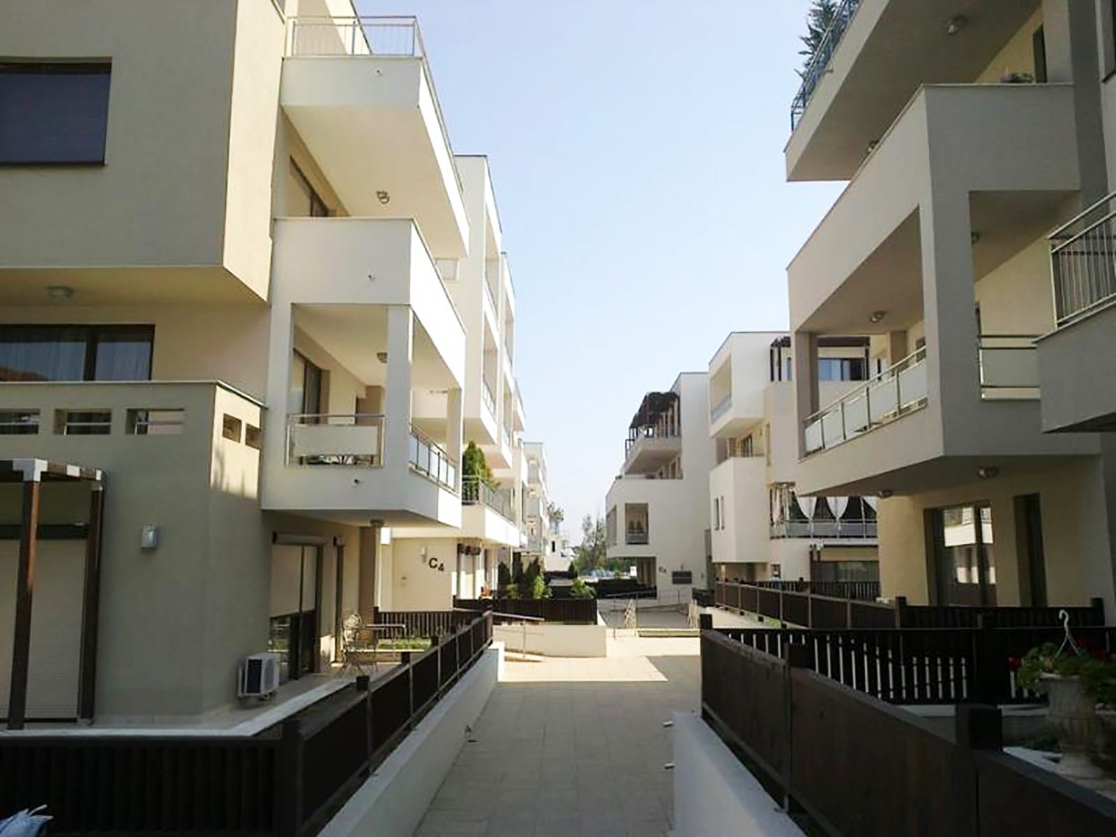 Aleea interioară dintre corpurile construite, cu gardurile brune ale grădinilor de la parter