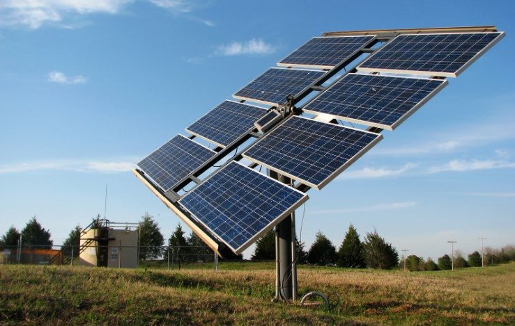 Panouri fotovoltaice pe urmăritor solar, lângă o construcție tehnică